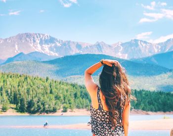 Rear view of young woman standing against mountains