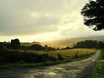 Road amidst field against sky