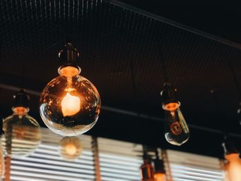 Low angle view of illuminated light bulbs hanging in room