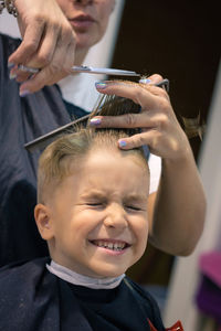 Woman cutting hair of boy at salon