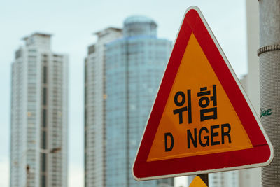 Danger road sign with skyscrapers in background