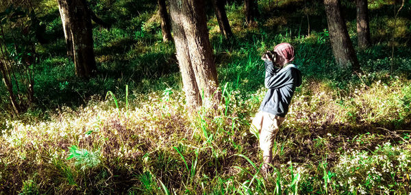 Woman standing on field in forest