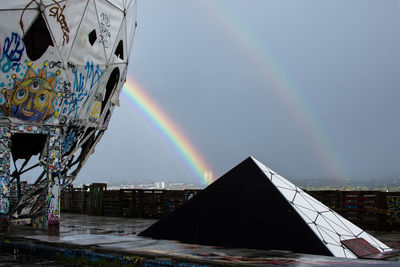 Rainbow over city against sky