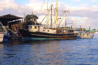 Boats moored at harbor against sky