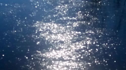 Defocused image of illuminated lights against sky at night