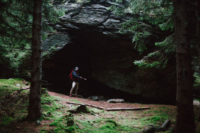 Man standing at cave in forest