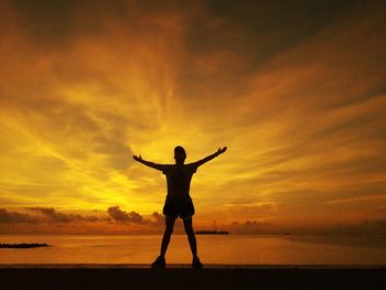 Silhouette man standing on beach against sky during sunset