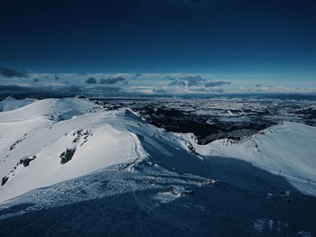 Aerial view of snowcapped mountains against blue sky