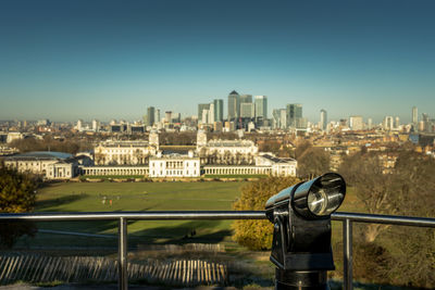 Telescope viewing point looking down on greenwich museum, with people playing in the park