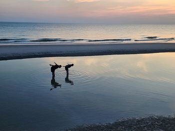 Silhouette woman walking at beach against sky during sunset