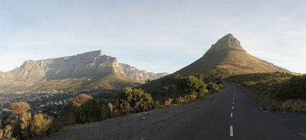 Country road by mountain against sky