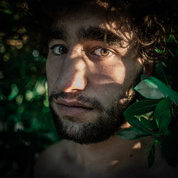 Close-up portrait of young man standing by plant