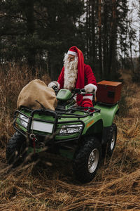 Man wearing santa costume riding lawn mower