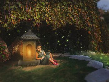 Woman sitting on cross against trees