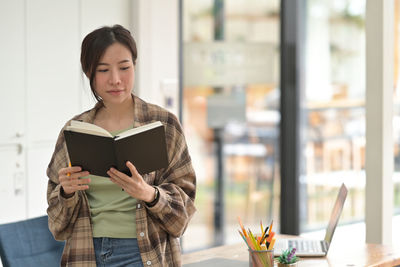 Young woman using phone while standing on table