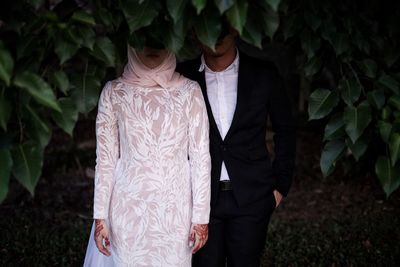 Couple standing trees on field