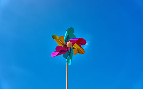 Low angle view of pinwheel against blue sky