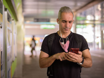 Young man using mobile phone while standing on mirror