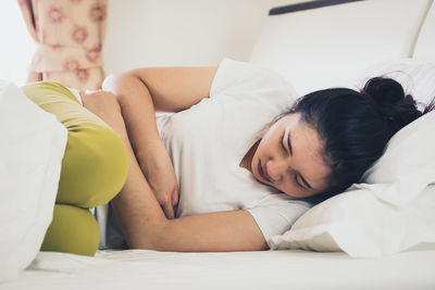 Woman with stomachache sleeping on bed