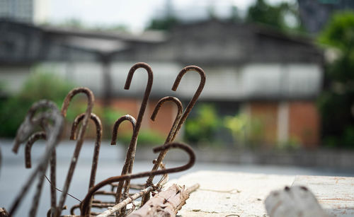 Close-up of rusty metal on street against buildings