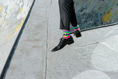 Low section of man wearing forma shoes skateboarding on footpath