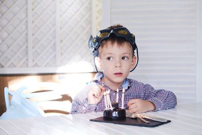 Cute boy wearing eyewear by cake at home