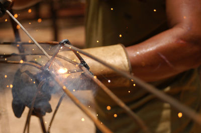 Mid section of man welding metal in workshop