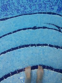 Low section of person standing in swimming pool