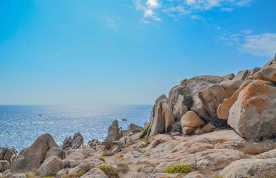 Rock formations by sea against blue sky