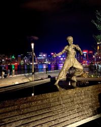 Statue against illuminated city at night