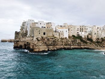 Buildings by sea against sky