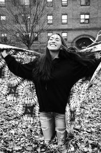 Young woman holding shawl while standing at park during autumn