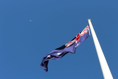 Low angle view of flags against clear blue sky