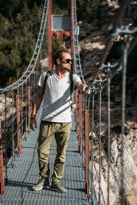 Portrait of middle-aged hiker passing by the hanging bridge and looking away. travel concept