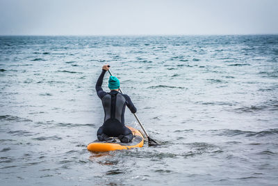 Rear view of man paddleboarding in sea