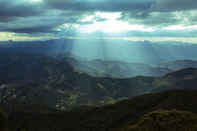 Sunlight streaming through clouds over landscape