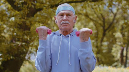 Determined senior man exercising with dumbbells in park