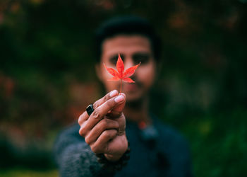 Close-up portrait of a man holding maple leaf