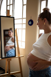 Side view of young woman using phone while sitting at home