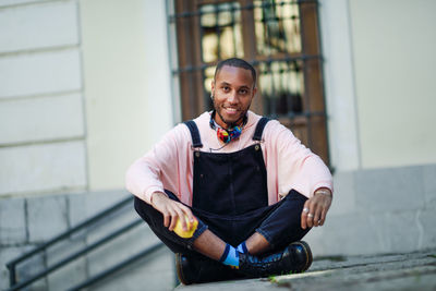 Portrait of smiling young man having apple against building