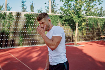 Side view of young man playing tennis