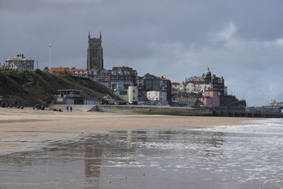 View of buildings by river against cloudy sky