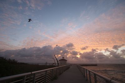 Pier on sea against sky during sunset