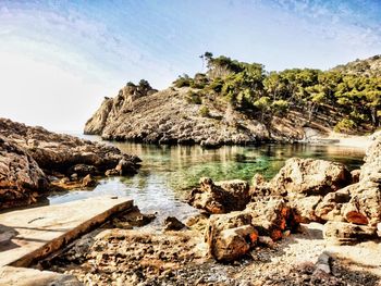 Rocks by lake against sky