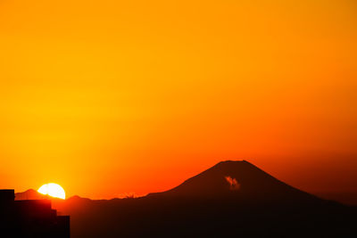 Scenic view of silhouette mountains against orange sky