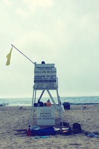 Information sign on beach against sky