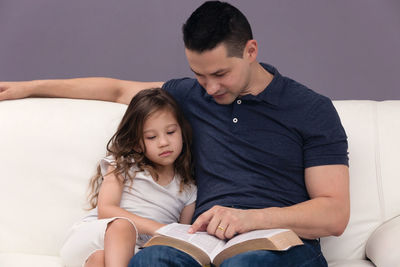 Portrait of a couple sitting against wall