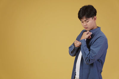 Boy standing against yellow wall