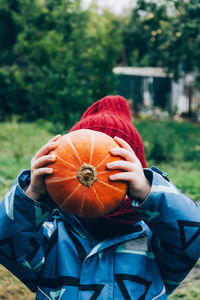 The child covers his face with a pumpkin. happy childhood in the village,harvesting for the holidays
