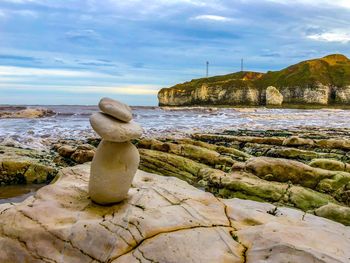 Rock formation on sea shore against sky